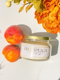 two peaches next to a jar of fresh peach face cream on a white surface