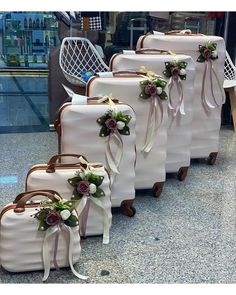 four pieces of luggage with ribbons and flowers on them sitting in front of an airport lobby