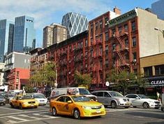 cars are driving down the street in front of tall buildings