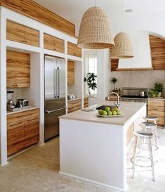 a kitchen with two hanging lights above the island and stools in front of it