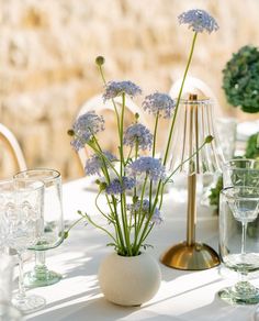 the table is set with blue flowers in vases and wine glasses, along with silverware