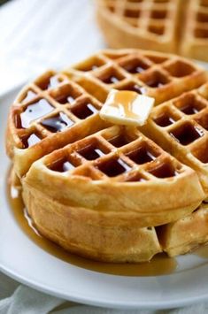 two waffles on a plate with syrup and butter drizzled on top