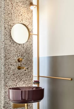 a bathroom with a sink, mirror and gold faucet next to a wall