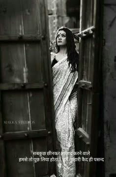 black and white photograph of a woman in sari leaning against an open wooden door