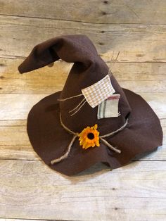 a brown witch hat with a sunflower on the front sits on a wooden floor