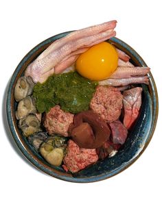 an assortment of meats and vegetables in a bowl with an egg on the top