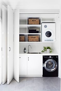 a washer and dryer in a white laundry room with open shelve