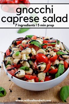 a white bowl filled with chopped vegetables on top of a wooden table next to tomatoes and basil