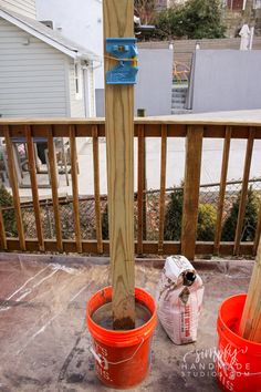 two buckets are sitting on the ground next to a wooden pole