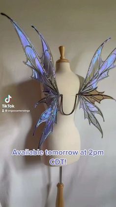 a white mannequin with blue and purple wings on it's head is shown