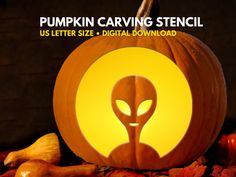 pumpkin carving stencil with an alien head in the center surrounded by autumn leaves