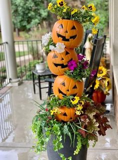 three pumpkins are stacked on top of each other with flowers in the bottom one