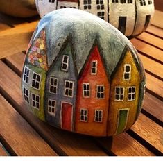 painted rocks with houses on them sitting on a wooden table in front of other decorations