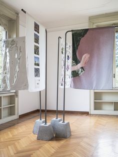 two sculptures in the middle of a room with wood flooring and paintings on the wall