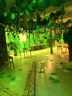 green balloons are hanging from the ceiling in a room with wooden flooring and chairs