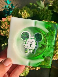 a hand holding up a green mickey mouse coaster