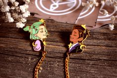 two cartoon characters are hanging from chains on a wooden table next to flowers and a pair of scissors