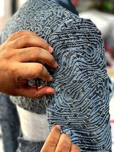 a man is working on a dress made out of blue beads and sequins