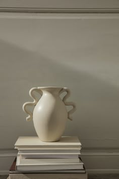 a white vase sitting on top of some books