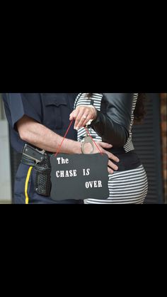 a police officer is holding a sign that says the chase is over with handcuffs on it