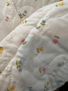 a close up of a white quilt with flowers on it