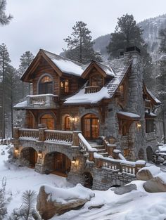 a large stone and wood house in the woods with snow on it's ground