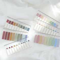 several different colors of paint are arranged on a white sheet with a ruler next to them