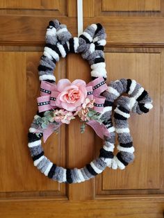 a wreath made out of yarn with flowers on the front and side, hanging from a wooden door