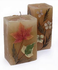 two candles decorated with leaves and flowers