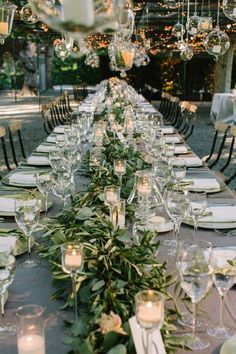 a long table is set with candles and place settings for an elegant dinner party in the garden