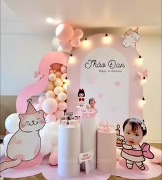 a pink and white birthday party with balloons, paper cutouts, decorations and an image of a cat on the wall