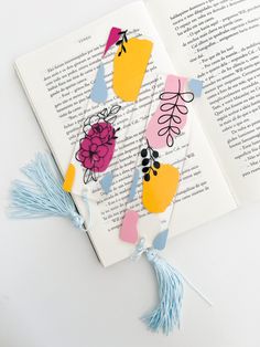 an open book with paper cutouts and tassels