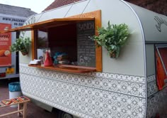 an old camper converted into a food truck with plants growing out of the window