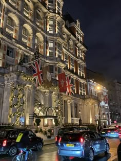 cars parked in front of a large building with christmas lights on it's side