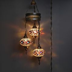 three lights hanging from the side of a wall