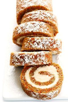 some food is laying out on a white plate with powdered sugar and cinnamon rolls