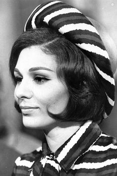 an old photo of a woman wearing a striped shirt and head scarf on her head