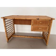 a desk made out of bamboo and wicker with two drawers on the bottom shelf