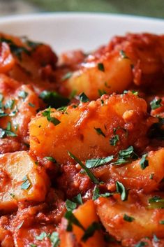 a white plate topped with potatoes covered in marinara sauce and parmesan cheese