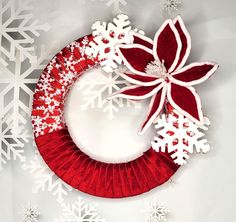 a red and white wreath with snowflakes on the top is hanging from a wall