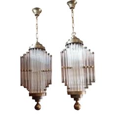 two glass and brass chandeliers hanging from chains on a white background in the style of art deco