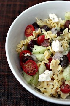 a white bowl filled with pasta salad on top of a table