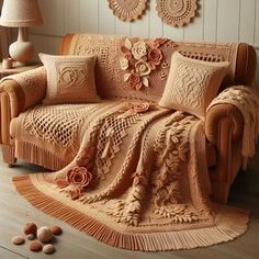 a living room with a couch covered in crocheted blankets and decorative wall hangings