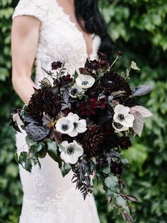 a woman holding a bouquet of flowers in her hands and wearing a white dress with black accents