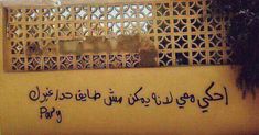 an arabic writing on the side of a building in front of a tree and fence