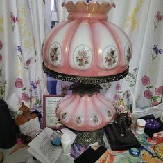 a pink and white vase sitting on top of a table next to other items in front of a window