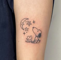 a small tattoo of a dog sitting on the ground with stars and moon above it