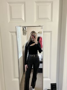 a woman taking a selfie in front of a mirror wearing black pants and white sneakers