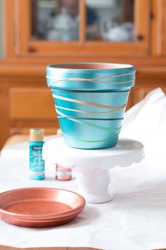 a blue glass bowl sitting on top of a white plate next to a wooden cabinet