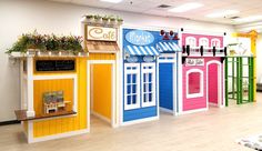 a row of brightly colored toy houses on display in a room with wooden floors and white walls